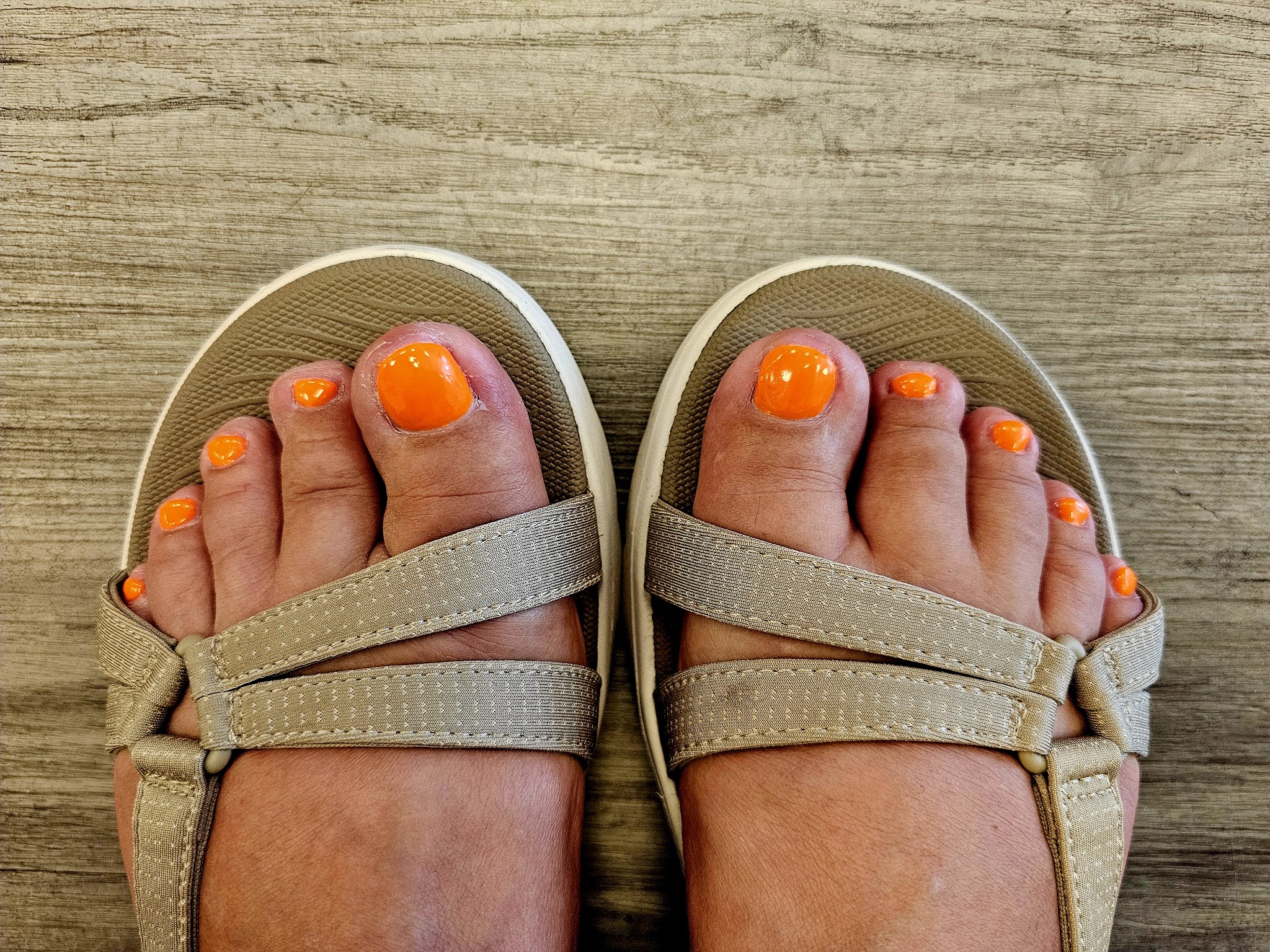Oranje gelakte teennagels in sandalen