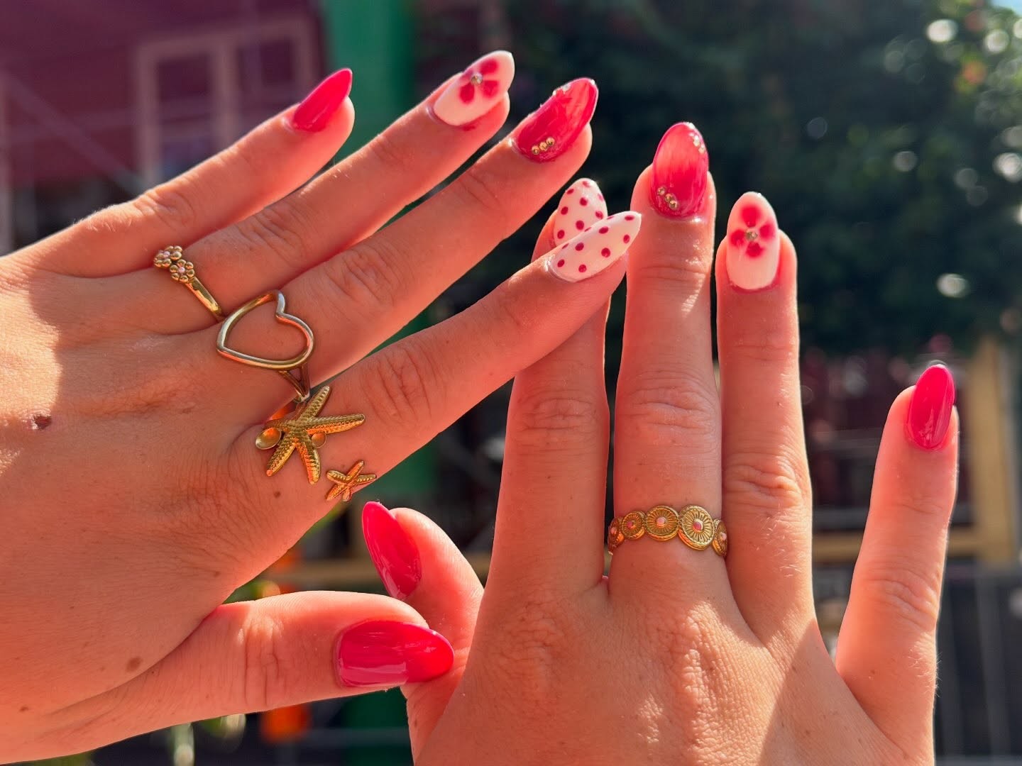 Twee handen met rode hartjes nailart en gouden ringen